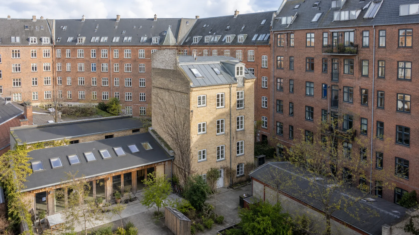 Københavnsk gårdrum med lave baghuse, et mellemstort sidehus og høje boligkarreer omkring samme byblok.