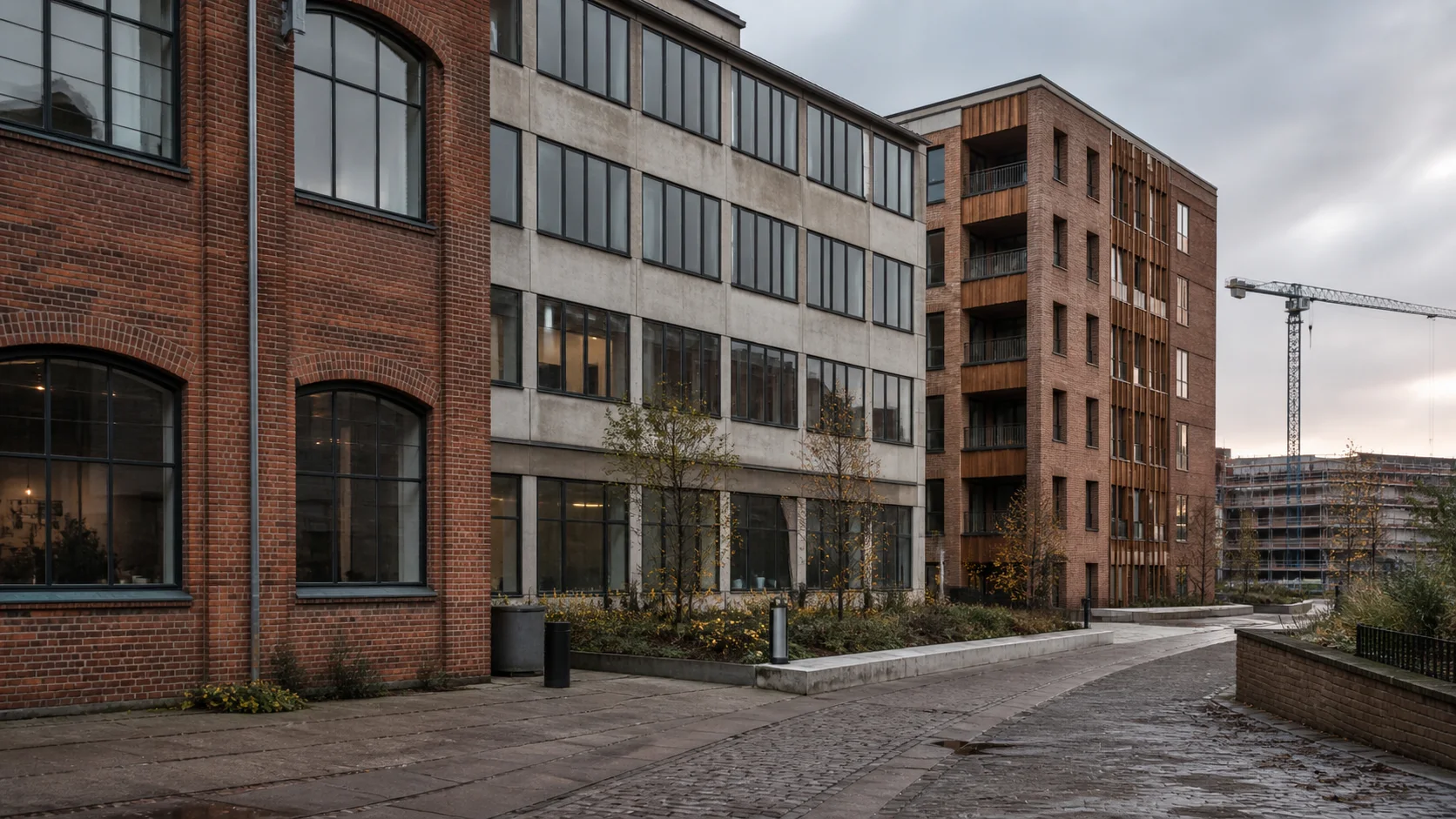 Københavnsk byblok med ældre erhvervsbygning i rød mursten, et modernistisk kontorhus og nyere boligbyggeri i samme gadeforløb.