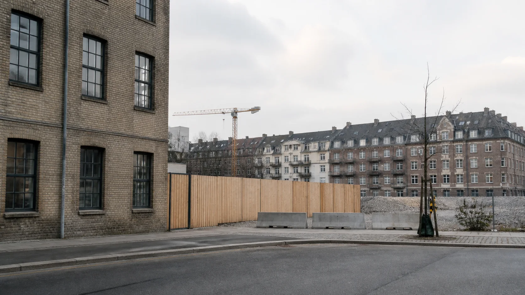 Københavnsk byblok med ældre murstensejendom, ryddet byggefelt og kran foran eksisterende boliger.