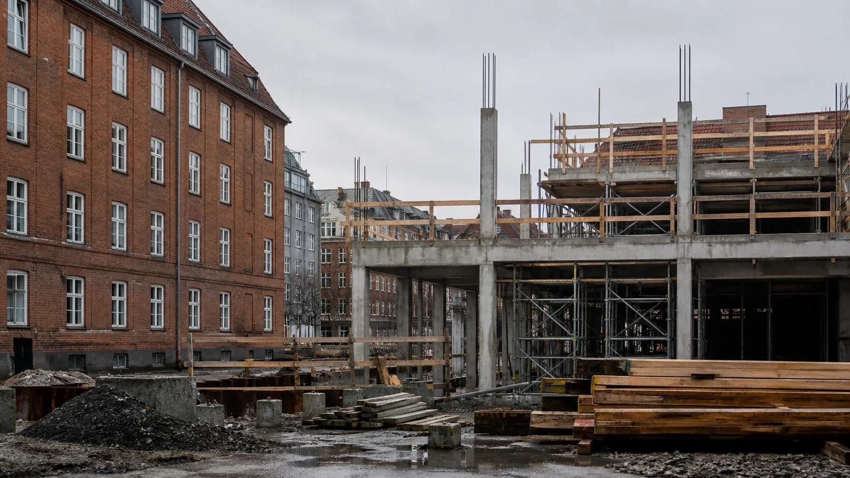 Københavnsk byggeplads med ny betonkonstruktion, råt træ og stillads ved siden af eksisterende røde murstensbygninger.
