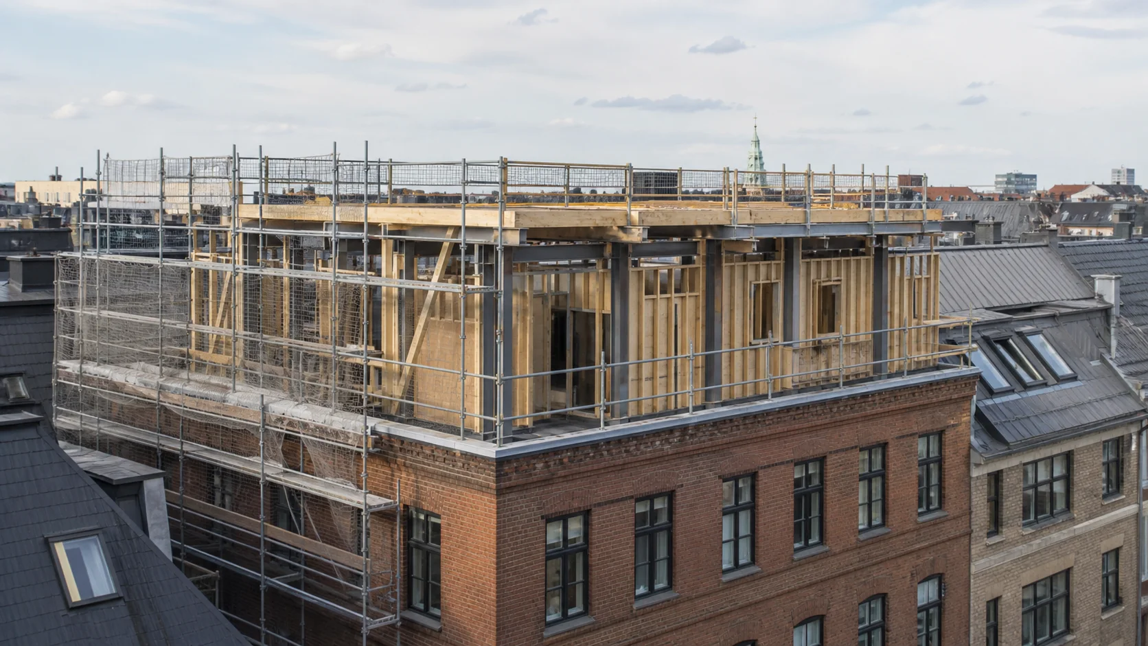 Ældre københavnsk murstensbygning med ny let træ- og stålkonstruktion under opførelse oven på den eksisterende bygning.